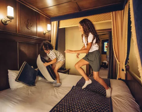 Les enfants sont sur le lit de la chambre de l'hôtel "Le Camp du Drap d'Or"