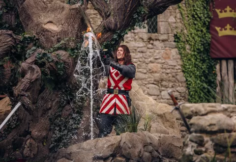 Tristan retirant Excalibur du rocher pour libérer le roi Arthur et les chevaliers de la table ronde dans le spectacle "L'Epée du Roi Arthur"