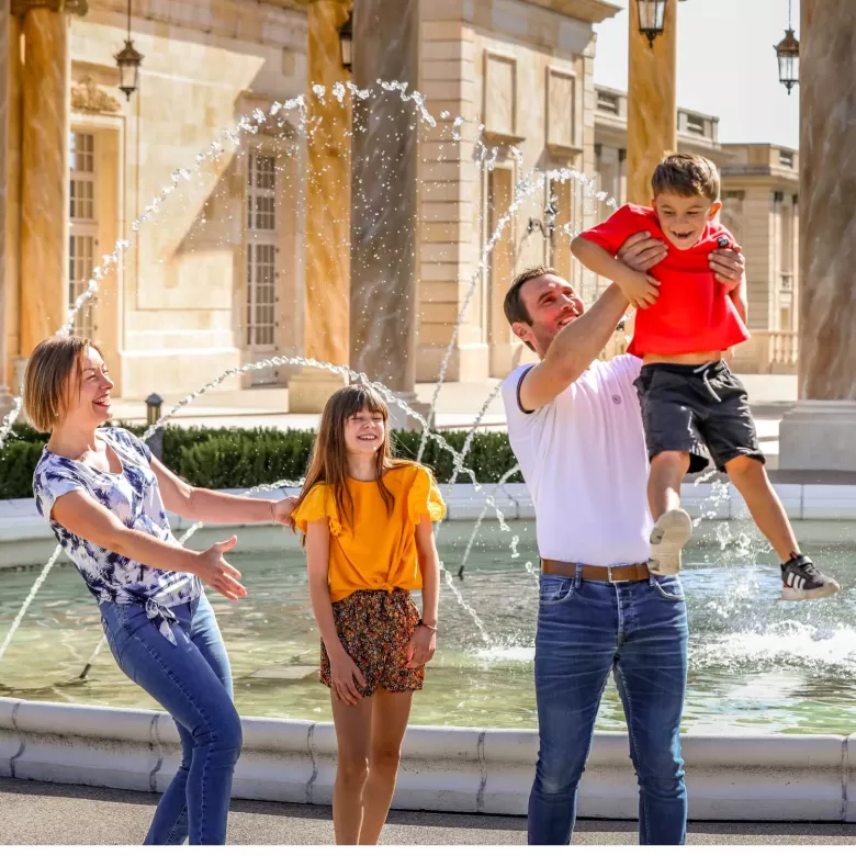 Famille souriant devant un hôtel du Puy du Fou grâce aux avantages CSE