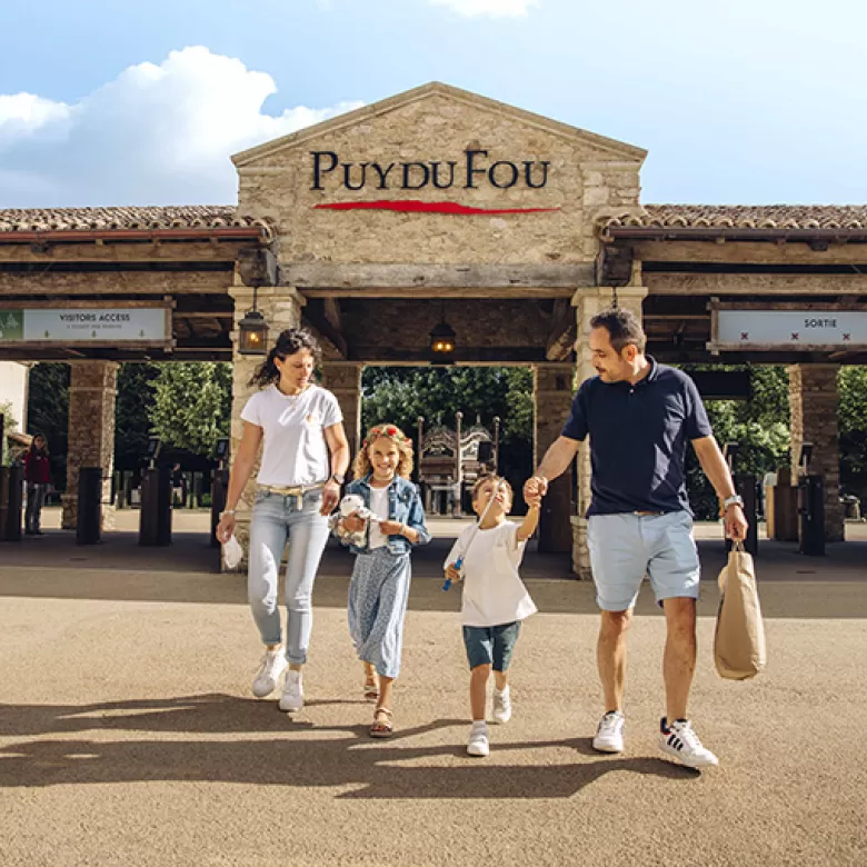 Famille avec de jeunes enfants qui sort du Puy du Fou avec ses achats à la main, heureuse d'avoir passé une bonne journée