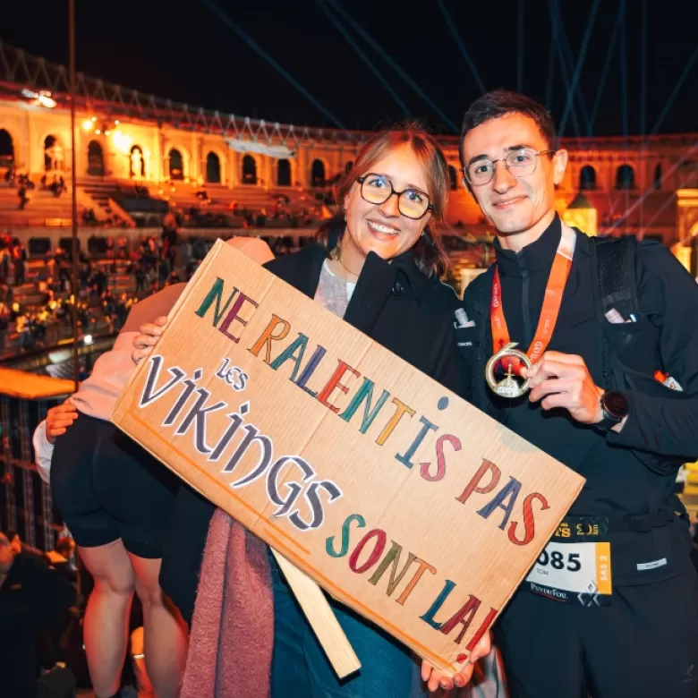 Accompagnateur encourage un coureur foulée des géants avec pancarte