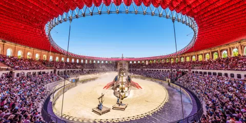 Visiteurs à l'ombre dans les tribunes dans l'arène romaine du Signe du Triomphe au Puy du Fou
