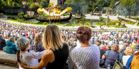 Famille composée d'un enfant sa mère et sa grand-mère devant le triflamme du spectacles des Vikings au Puy du Fou