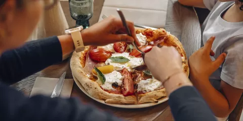 Famille en train de manger une pizza autour du Puy du Fou pour profiter de leur séjour en Vendée