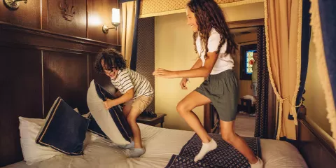 Les enfants sont sur le lit de la chambre de l'hôtel "Le Camp du Drap d'Or"