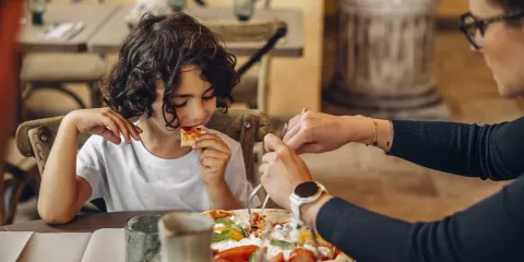 Jeune garçon mangeant une pizza dans l'un des restaurants du Puy du Fou