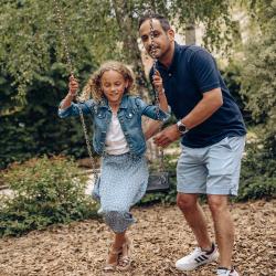 Une fille avec son père joue à la balançoire au Repaire des Enfants.