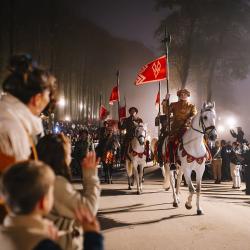 Une famille regarde le Cortège Royal de la Frairie de la Toussaint précédant le spectacle nocturne "Les Noces de Feu"