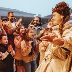 Une famillle qui applaudit la reine Eléonore à son arrivée au spectacle éphémère "La Frairie de la Toussaint"