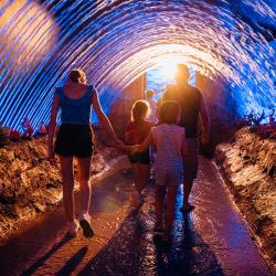 Une famille déambule dans le spectacle "Le Mystère de la Pérouse" et traverse une cascade d'eau.